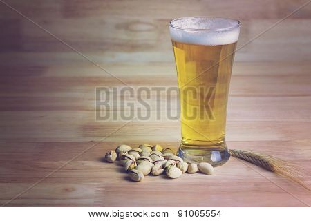 Glass Beer And Pistachios On Wood Background