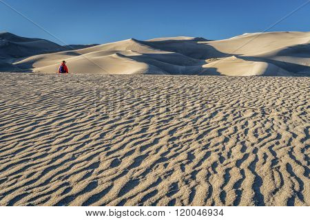 Lost in the sea of sand -  a lonely hiker in a dunefield in Great Sand Dunes National Park, Colorado