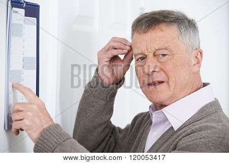 Confused Senior Man With Dementia Looking At Wall Calendar