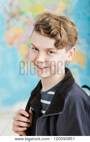 Smiling Boy Standing In Classroom Holding Knapsack