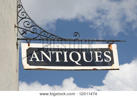 Old, rusty 'Antiques' wall sign on wrought iron bracket