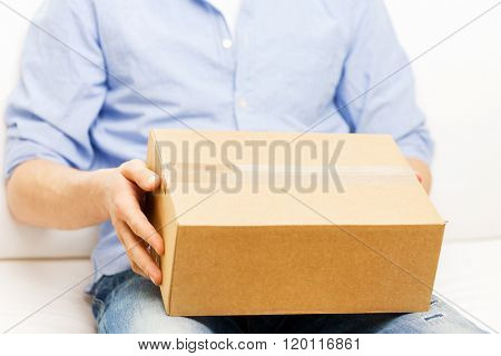 delivery, mail and people concept - close up of man with cardboard box or parcel at home