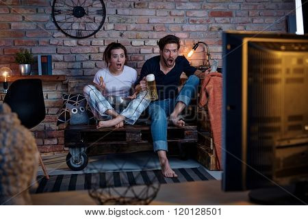 Young couple watching tv at home, jittering.