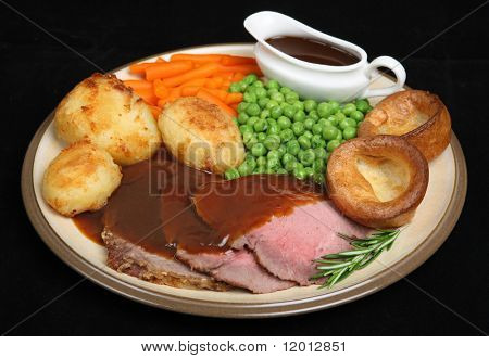 Arrosto di cena di carne di manzo con Yorkshire pudding e gravyboat individuali.