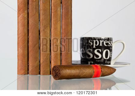 Different cigars and cup of coffee on a glass table and white background