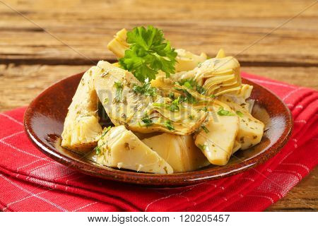 plate of marinated artichokes on red dishtowel - close up