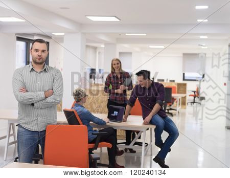 portrait of young businessman in casual clothes at modern  startup business office space,  team of people working together in background