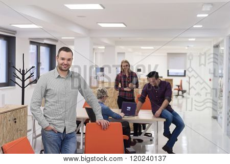 portrait of young businessman in casual clothes at modern  startup business office space,  team of people working together in background