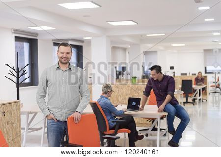 portrait of young businessman in casual clothes at modern  startup business office space,  team of people working together in background
