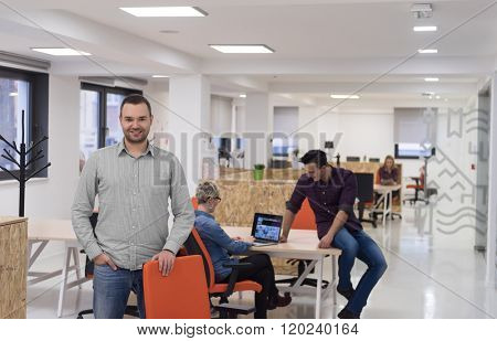 portrait of young businessman in casual clothes at modern  startup business office space,  team of people working together in background