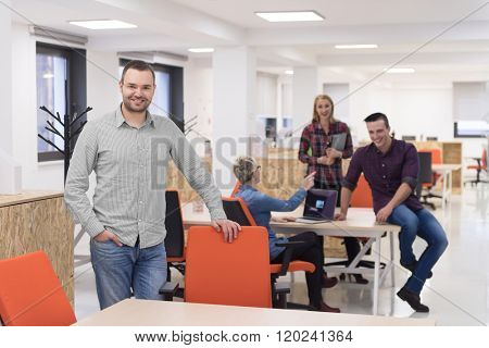 portrait of young businessman in casual clothes at modern  startup business office space,  team of people working together in background