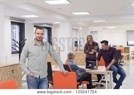 portrait of young businessman in casual clothes at modern  startup business office space,  team of people working together in background