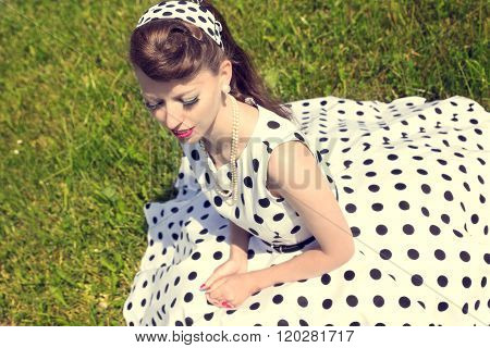 Woman With A Petticoat Dress, A Braid And A Suicide Roll Sitting On The Meadow