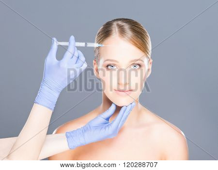 Doctor injecting in a beautiful face of a young woman. Plastic surgery concept.