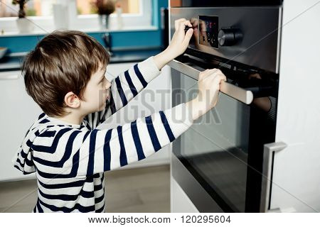 Boy Dangerously Playing With The Knobs On The Oven