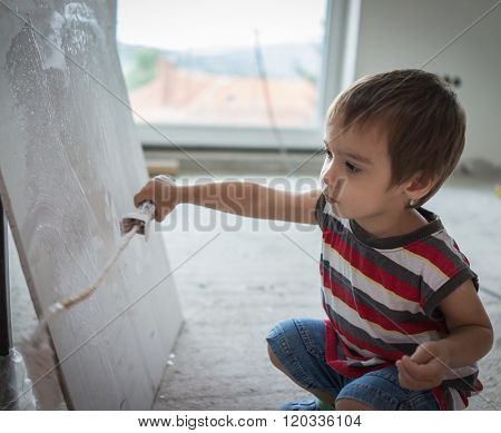 Little cute boy painting on a wall