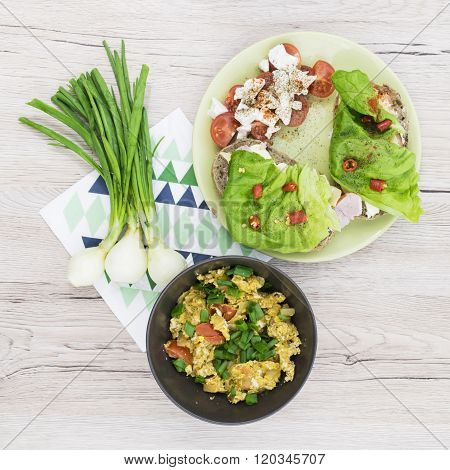 Scrambled eggs in the brown bowl. Sandwiches with lettuce and hot peppers. Wooden background. Top vi