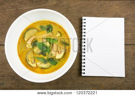 The delicious homemade Thai green curry with pork (Gang Keaw Wan) in white bowl and blank note book