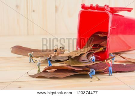 Image Of Mini Figure Dolls Worker Collect Dry Leaves Into The Red Recycle Bin .