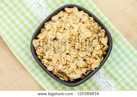 Healthy Homemade Granola in black cup on tablecloth.