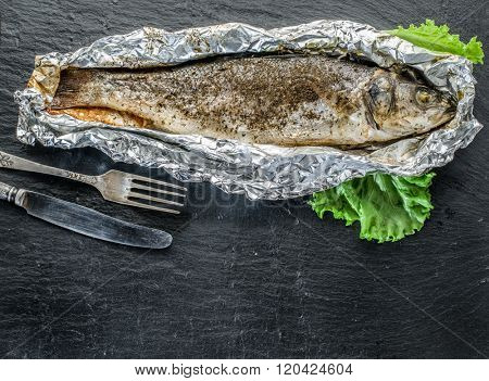 Grilled sea bass fish on the gray table.