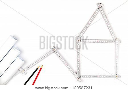 White Meter Tool Forming A House, Two Drawing Pencils And Paper Drawings On White Background
