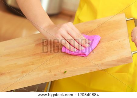 Woman Cleaning Wooden Cutting Board With Rag