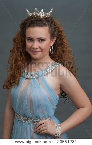 Teen beauty in blue dress poised with crown