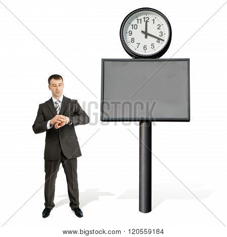 Businessman looking at his hand near big clock