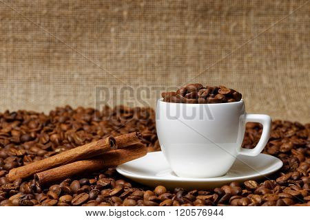 Coffee Cup Full Of Coffee Beans And Cinnamon Sticks