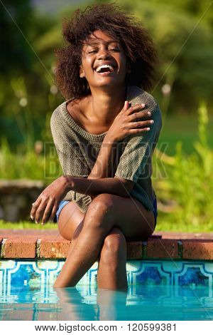 Young Woman Sitting By Pool With Feet In Water