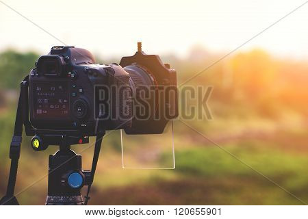 DSLR camera with gradient filter focus on sunrise landscape view.