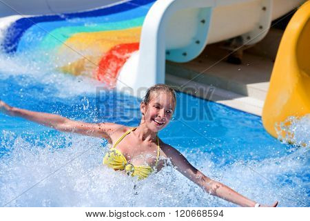 Happt teen girl on water slide at aquapark. Summer holiday.