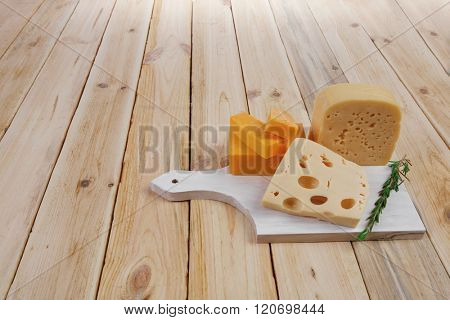 various types of fresh raw aged delicatessen cheese on white plate over light wooden table cheddar edam swiss