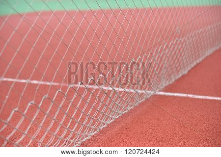 Detail Of Net Tennis On Field Made From Red Granule Rubbe. Selective Focus