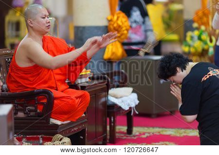 SANGKHLABURI, THAILAND, JANUARY 24, 2016 :  A skilled Buddhist monk is blessing a woman  by throwing a rosary necklace around his neck in the Wat Wang Wiwekaram temple, Sanghklaburi, Thailand