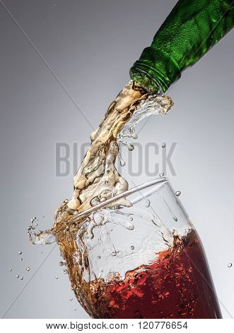 Jet of beer from  the bottle into the glass on the grey background