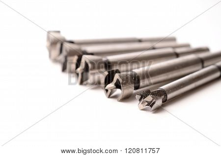 Selective focus on an assortment of fostner bits on an white background