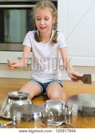 Little girl playing drums on pots and pans in the kitchen.** Note: Visible grain at 100%, best at smaller sizes