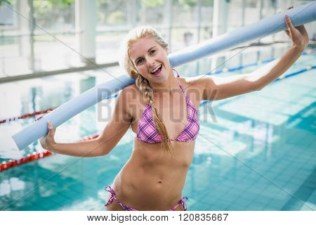Attractive woman holding foam roll around her neck at the pool