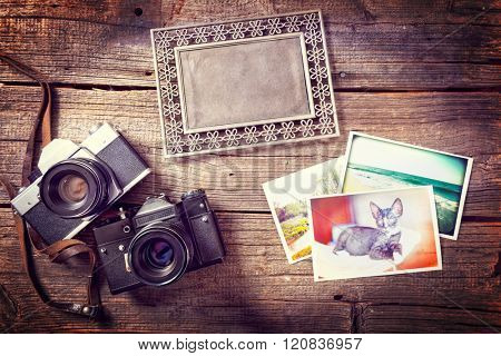 Old photographic camers with vintage prints and photo frame on wooden desk