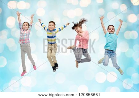 happiness, childhood, freedom, movement and people concept - happy little children jumping in air over blue holidays lights background