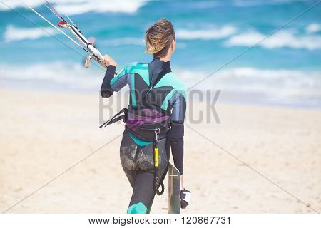 Female kiteboarder with kiteboarding equipment.