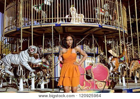 cool real teenage girl with candy near carousels at amusement park walking, having fun