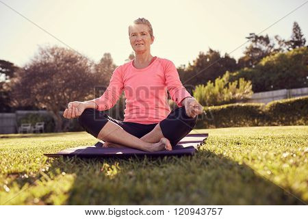 Senior woman doing yoga breathing exercises outdoors with sunfla