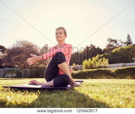 Active senior woman doing a yoga twist outdoors