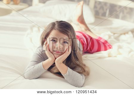 Portrait of a cute little girl, waking up and lying in bed in the morning