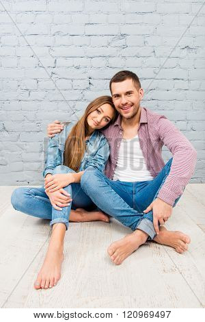 Handsome Man Sitting On The Floor And Embracing His Girlfriend