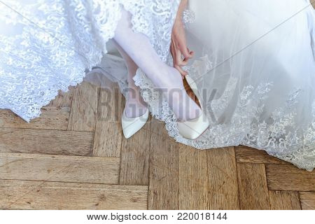 the bride wears white shoes on foot in the wedding day. close-up shoot