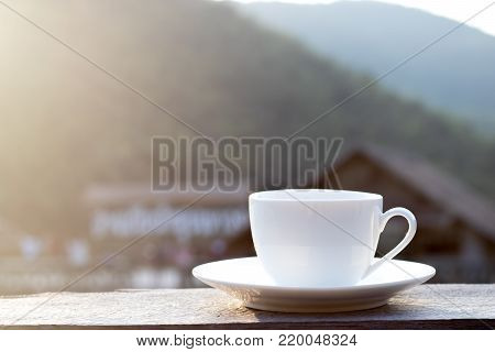 cup of hot coffee for brackfast on wooden balcony near river and mountain background